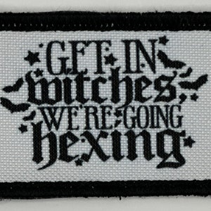 Op de afbeelding: Een witte stoffen patch met zwarte geborduurde tekst die "Get in witches, we're going hexing" luidt. De patch heeft een zwarte rand.