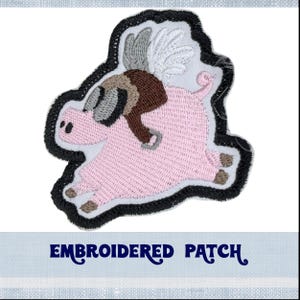 May include: Embroidered patch of a pink pig wearing a brown aviator helmet and goggles, with white wings. The pig is flying and has a black outline.