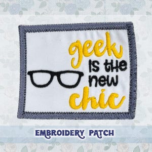 Puede incluir: Parche bordado con borde gris y fondo blanco. El texto "geek is the new chic" está bordado en amarillo. Un par de gafas negras está bordado sobre el texto. El texto "EMBROIDERY PATCH" está impreso debajo del parche.