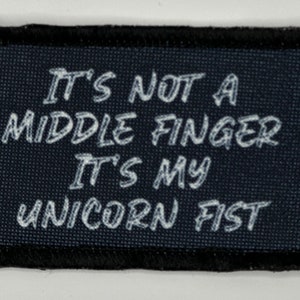 May include: Black patch with white text that reads "It's not a middle finger it's my unicorn fist."