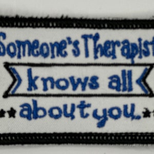 May include: White embroidered patch with black border. The text reads "Someone's Therapist knows all about you."