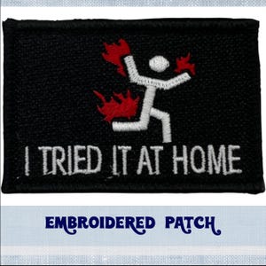 May include: Black embroidered patch with a white stick figure on fire and the text "I TRIED IT AT HOME".
