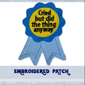 May include: Blue and yellow embroidered patch with the text "Cried but did the thing anyway".