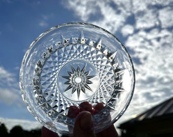 May include: A clear glass dish with a starburst pattern and a raised rim. The dish is marked "Aroostoc USA".