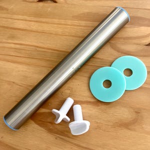 May include: A stainless steel rolling pin with blue accents, two turquoise round spacers, and two white screws are arranged on a wooden surface. The rolling pin is cylindrical and appears to be about 12 inches long.