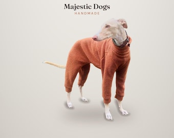 Puede incluir: Un perro de color claro lleva puesto un mono de forro polar color óxido de manga larga con puños acanalados. Sobre el perro, el texto dice Majestic Dogs HANDMADE en letras marrón oscuro. El perro lleva un collar oscuro en el cuello.
