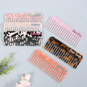 May include: A selection of personalised combs in diverse colours and patterns. The combs display names such as "Emilie," "Ashley," "Susan," "Maille," and "Jessica." One comb has "Your Logo" printed on it. The combs are in shades of pink, white, black, and tortoiseshell.