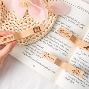 May include: Wooden bookmarks with personalized names and decorative designs. One bookmark reads "Tammy", another "Bailey", and a third "Racina". Other bookmarks feature a mountain, a book, and stars.