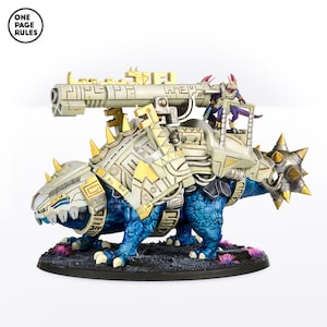 May include: A blue and white miniature wargaming figure of a reptilian creature with a gold and white armored shell. The creature is carrying a large cannon on its back, and a smaller figure is standing on top of the cannon.