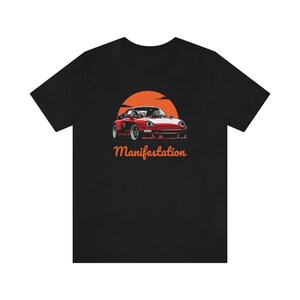 May include: Black t-shirt with a red sports car graphic and the word "Manifestation" in orange text.