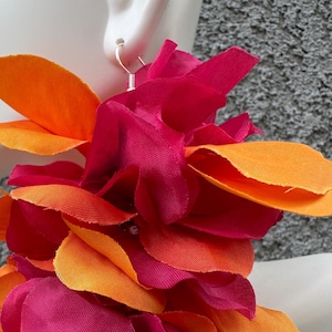 Puede incluir: Un par de pendientes grandes de declaración hechos con pétalos de tela rosa y naranja. Los pendientes están diseñados para parecer flores.