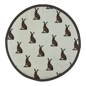 May include: Round brown and white pot holder with a repeating pattern of brown hares. The pot holder has a dark brown border.