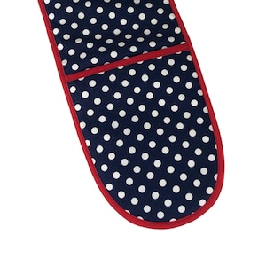 May include: A blue oven mitt with white polka dots and a red trim. The mitt has a pocket on the back.