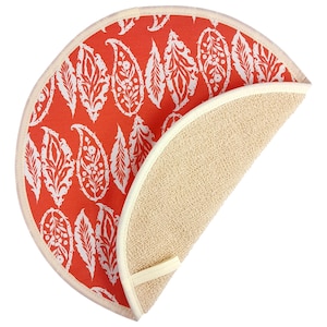 May include: A round, orange and white patterned hot pad with a beige terry cloth backing. The hot pad is folded in half, showing both sides.