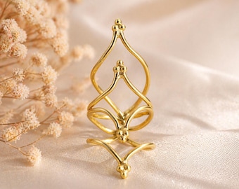 May include: A gold-colored ring with an intricate, openwork design. The ring features a series of interconnected, curved lines and small, decorative spheres. The ring's design is symmetrical and elegant, suitable for a variety of occasions.