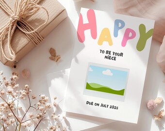 May include: A white card with the word "HAPPY" in colorful letters, a picture frame with a green landscape, and the text "To be your niece, Due on July 2025".