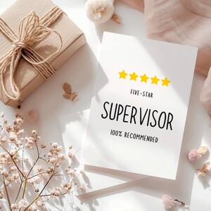 以下が含まれることがあります： 「FIVE-STAR SUPERVISOR 100% RECOMMENDED」の文字と5つの黄色の星が描かれた白いカード。紐で結ばれたギフトボックスとドライフラワーが背景にあります。