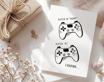 May include: A white card with black text and illustrations of two video game controllers. The text reads "Player #1 "Daddy" Player #2 Loading..."