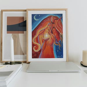 May include: Framed art print featuring a woman with long, flowing red hair holding a glowing star, with a horse. The artwork is set against a blue night sky with a crescent moon and stars. The color palette includes reds, oranges, and blues.