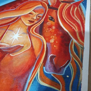 May include: An original painting depicts a woman with flowing red hair embracing a red horse. The woman holds a glowing star. The background is a deep blue with a crescent moon and stars. The artwork is on canvas.