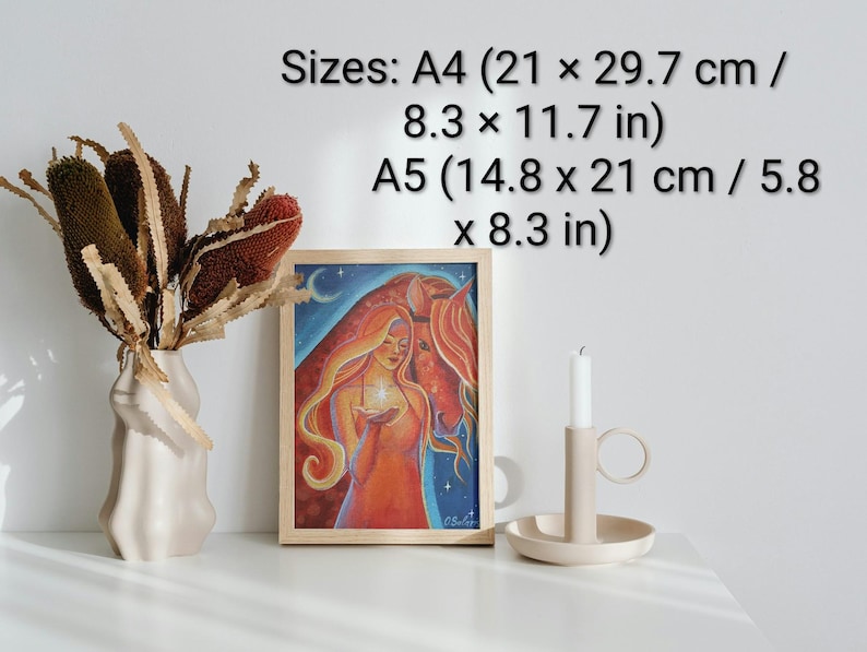 May include: A framed art print featuring a woman with long red hair holding a glowing orb, with a horse in the background. The print is in a wooden frame. Sizes: A4 (8.3 x 11.7 in) and A5 (5.8 x 8.3 in). A vase with dried flowers and a candle holder are also present.
