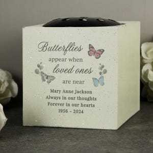 May include: A light green memorial flower vase with a black top. The vase features watercolor butterflies and the text "Butterflies appear when loved ones are near." It includes a name and dates.