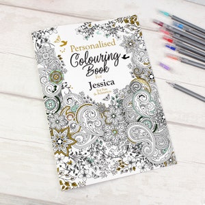 May include: A personalised colouring book for Jessica, featuring a detailed floral and paisley design in black, white, gold, and teal. Several coloured pens are visible, alongside a single grey pen.