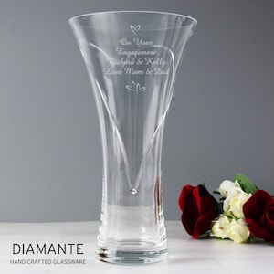 May include: A clear glass vase with a heart-shaped design and a single crystal embellishment. The vase is engraved with the text "On Your Engagement Richard & Kelly Love Mum & Dad".