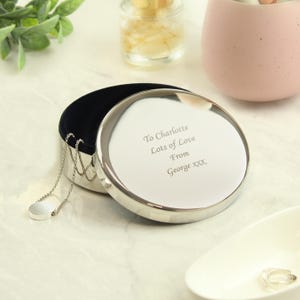 May include: A silver round trinket box with a velvet interior. The lid is engraved with the message "To Charlotte Lots of Love From George XXX".