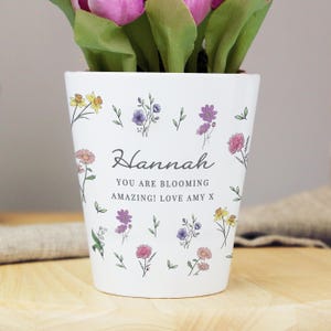 May include: White ceramic flower pot with a floral pattern and the text "Hannah You are blooming amazing! Love Amy x".