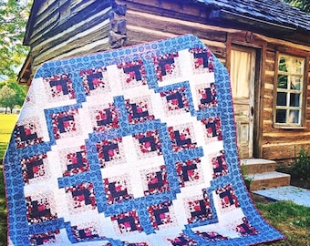 May include: A rectangular quilt featuring a log cabin block pattern with a repeating color scheme of navy blue, white, and floral pink. The fabric displays intricate patterns including small dots, paisley swirls, and floral motifs throughout the design.