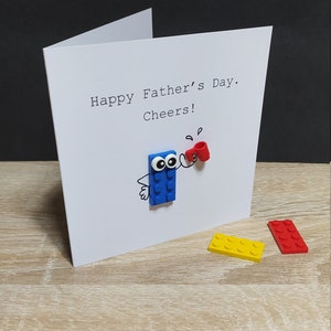 Proost! Verjaardagskaart (of welke gelegenheid dan ook) met echte LEGO® onderdelen, met een stenen figuur die een beker vasthoudt en "Proost!"
