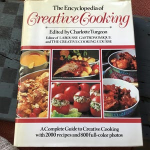 May include: The Encyclopedia of Creative Cooking, edited by Charlotte Turgeon, is a hardcover book featuring a white cover with red text and borders. The front displays multiple food photographs, including stuffed tomatoes, roasted meat, and bowls.
