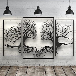 Könnte beinhalten: Drei schwarze Wandbilder aus Metall, die zwei stilisierte Bäume mit ineinander verschlungenen Wurzeln darstellen, die die Form von zwei sich anschauenden Gesichtern bilden.