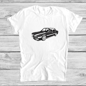 May include: A white t-shirt featuring a black silhouette of a car printed on the front.