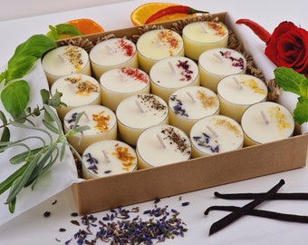 May include: A set of 15 small, white tea light candles in a cardboard box. The candles are arranged in three rows of five. Each candle has a different dried flower or herb embedded in the wax. The box is lined with brown paper and has a white paper lid.