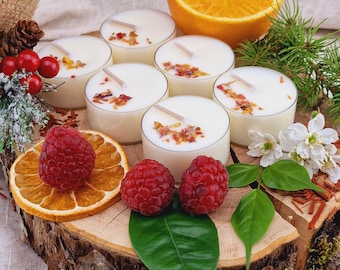 May include: A decorative arrangement featuring seven white tea light candles with dried petals. The candles are displayed on a wooden slice with fresh raspberries, orange slices, and greenery, creating a natural, aromatic display.