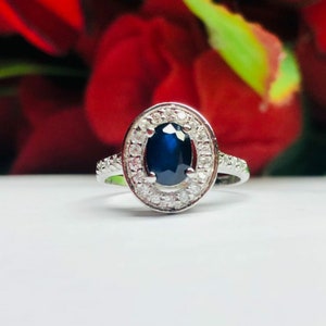 May include: A silver ring with a large oval blue sapphire surrounded by a halo of smaller diamonds.