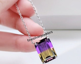 Può includere: Una collana a catena in argento con una pietra preziosa ametrino rettangolare taglio smeraldo con distinte zone di colore viola e giallo. Il ciondolo è tenuto da quattro griffe in argento. Il testo finesilverjewelers è stampato vicino alla parte superiore.