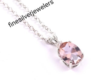 May include: A silver chain necklace with a pink oval pendant featuring a clear crystal. The pendant is set in a silver bezel with small clear stones around the edge. The text "finesilverjewelers" is visible in the image.