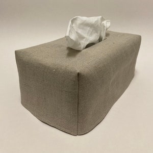 May include: A beige linen tissue box cover with a white tissue box inside.