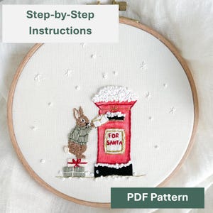 Può includere: Ricamo su telaio raffigurante un coniglietto che imbuca una lettera in una cassetta postale rossa con la scritta "FOR SANTA". Il disegno include fiocchi di neve e regali. Sono visibili anche i testi "Step-by-Step Instructions" e "PDF Pattern".