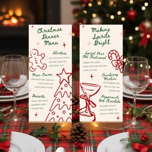 May include: Two cream-colored Christmas dinner menus with red illustrations and text. The menus are on a wooden base, with wine glasses and a festive table setting. The menus read "Christmas Dinner Menu" and "Making Spirits Bright."