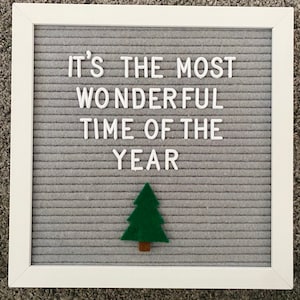 May include: A gray felt letter board with white letters spelling "It's the most wonderful time of the year". A green felt Christmas tree is below the text.