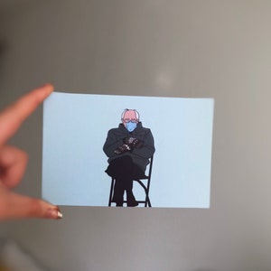 May include: A drawing of a person wearing a blue face mask and a dark jacket, sitting in a chair with their arms crossed.