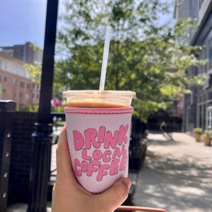 May include: Pink insulated coffee cup sleeve with the text "DRINK LOCAL COFFEE" in pink bubble letters.