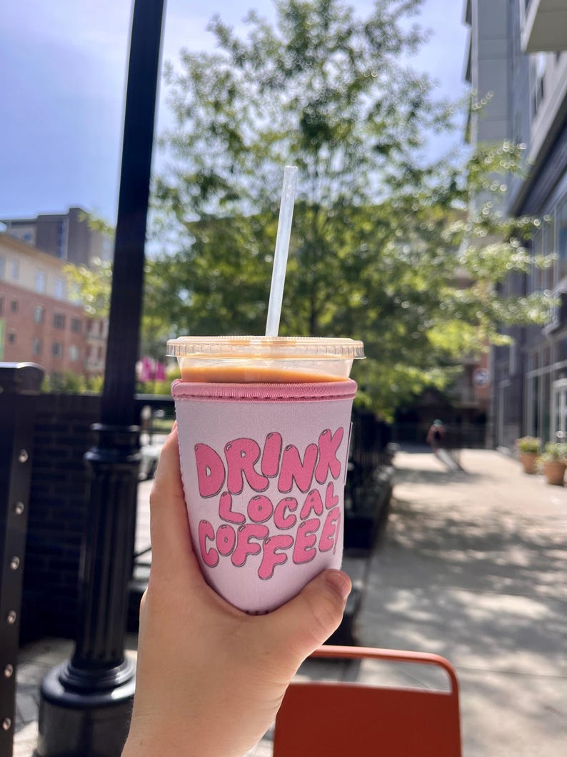 May include: Pink insulated coffee cup sleeve with the text "DRINK LOCAL COFFEE" in pink bubble letters.