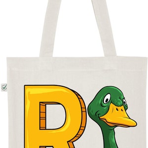 May include: A white canvas tote bag with a yellow letter R and a green duck head illustration. The duck has a yellow beak and white feathers around its neck.