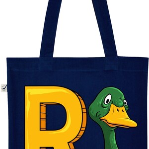 May include: A navy blue tote bag with a yellow letter R and a green duck with a white beak and white feathers on its neck. The duck is looking to the right.