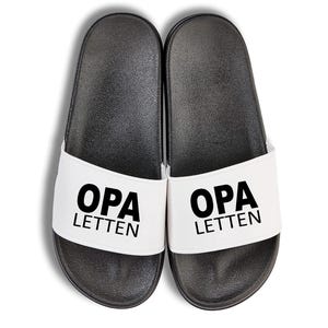 Könnte beinhalten: Ein Paar schwarze und weiße Schlappen mit dem Text "OPA LETTEN" auf der Vorderseite.